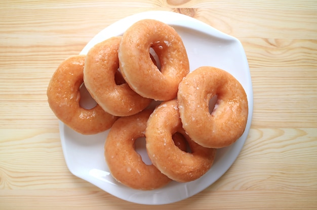 Vue de dessus de beignets glacés au sucre servis sur une plaque blanche sur une table en bois