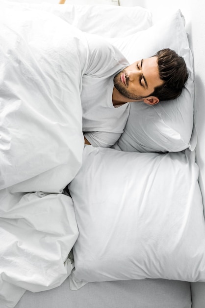 Vue de dessus d'un bel homme dormant dans son lit le matin