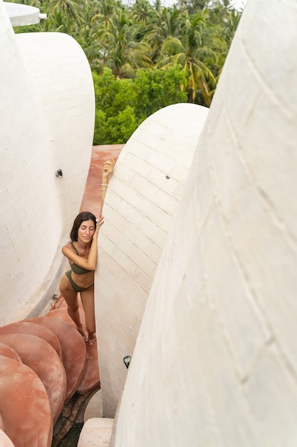 Vue de dessus d'une belle femme sereine aux cheveux noirs somnolant près d'un bâtiment en calcaire blanc