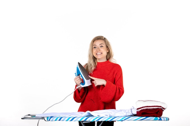 Vue de dessus de la belle jeune femme souriante tenant et pointant le fer sur fond blanc