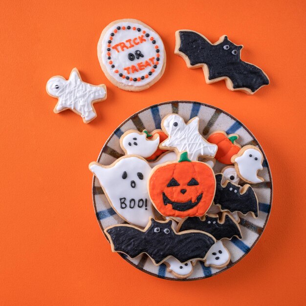 Vue de dessus des biscuits au sucre glace décorés de fête d'Halloween sur fond orange