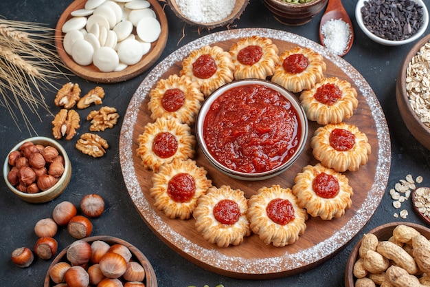 vue de dessus biscuits avec confiture et bol de confiture sur planche de bois avoine noisettes et bonbons dans des bols noix sur table