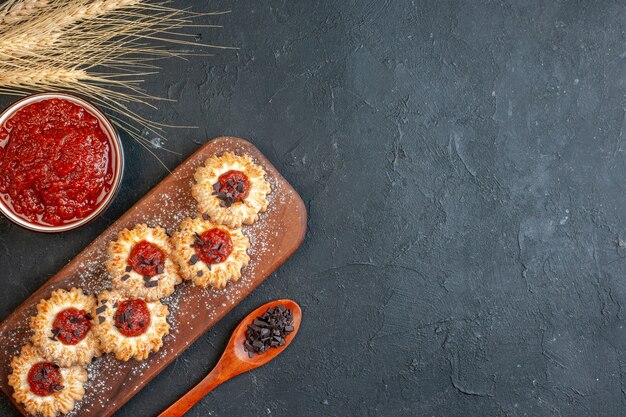 vue de dessus biscuits avec confiture sur planche de bois confiture dans un bol épis de blé sopoon en bois sur fond sombre avec espace libre