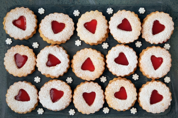 Photo vue de dessus des biscuits de noël linzer traditionnels avec de la confiture rouge sur noir