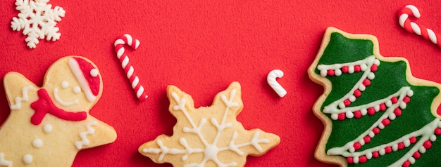 Vue de dessus des biscuits de pain d'épice de Noël décorés sur fond de table rouge avec espace de copie, concept de célébration de vacances.