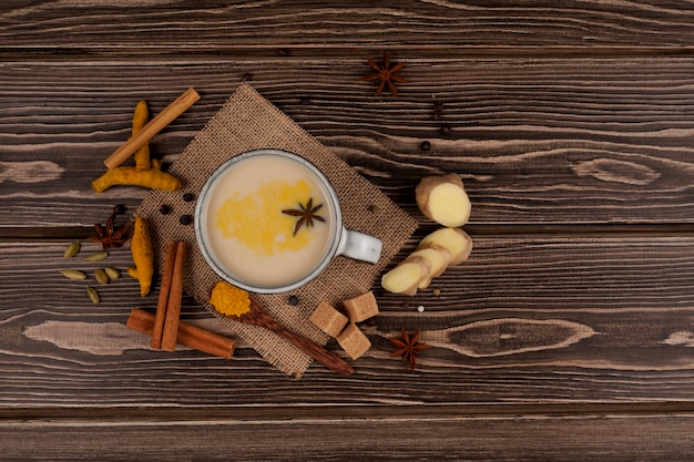 Vue de dessus sur la boisson traditionnelle indienne masala chai, thé au lait et épices sur bois