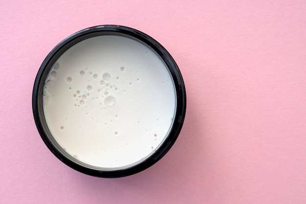 Vue de dessus de la boîte ronde avec mousse de cire crème blanche pour les soins quotidiens sur fond rose