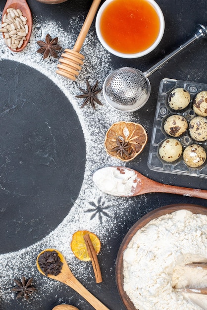 Vue de dessus des bols de cercle de farine saupoudrés avec des cuillères en bois de farine de miel sur la table