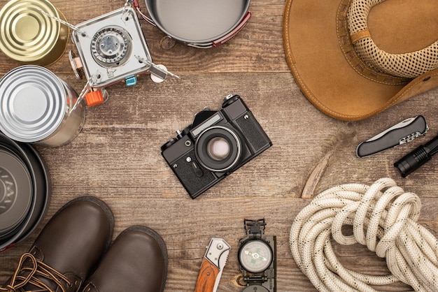 Vue de dessus des bottes de chapeau de caméra photo et de l'équipement de randonnée sur une table en bois