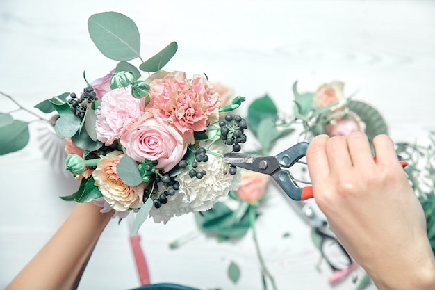 Vue de dessus bouchent les fleurs coupées femelles debout au comptoir. Organiser diverses fleurs dans un bouquet frais moderne. Copiez l'espace. magasin de fleurs, entreprise, vente et concept professionnel de fleuriste