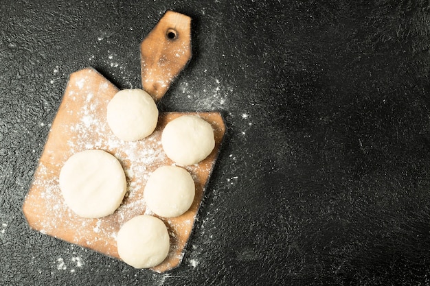 Vue de dessus des boules de pâte sur une plaque en bois sur fond noir