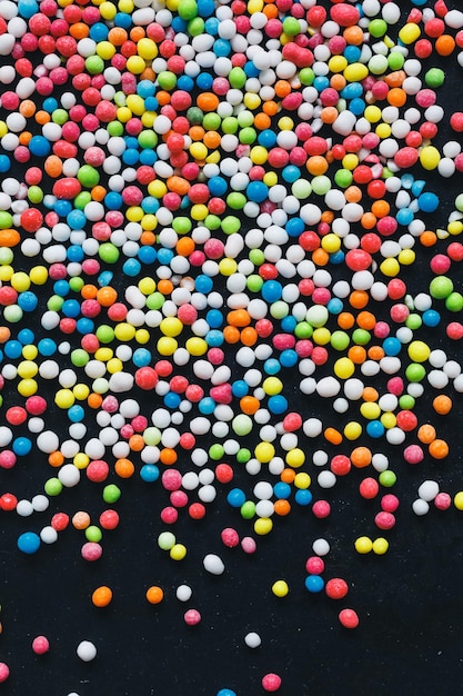 Vue de dessus de boules de sucre multicolores éparpillées sur un fond métallique sombre et une place pour votre texte