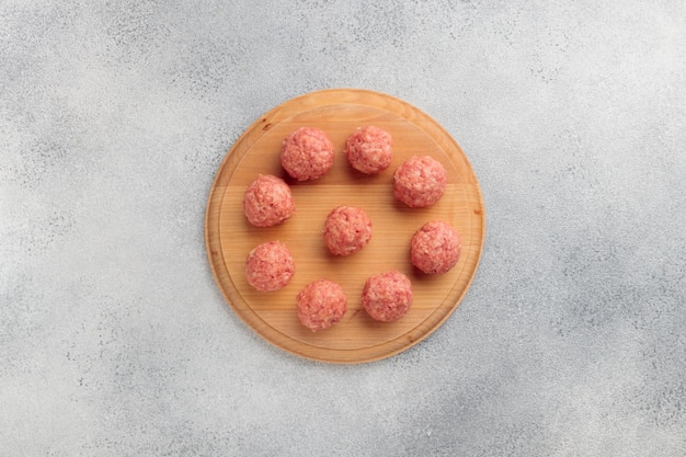 Vue de dessus des boulettes de viande crue sur une planche de bois