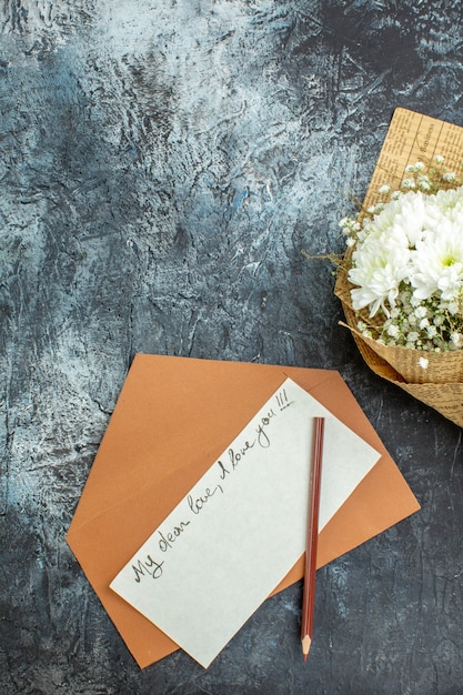 vue de dessus bouquet de fleurs lettre d'amour enveloppe crayon sur fond sombre espace libre