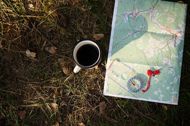 Vue de dessus de la boussole de la carte et de la tasse de boisson sur l'herbe