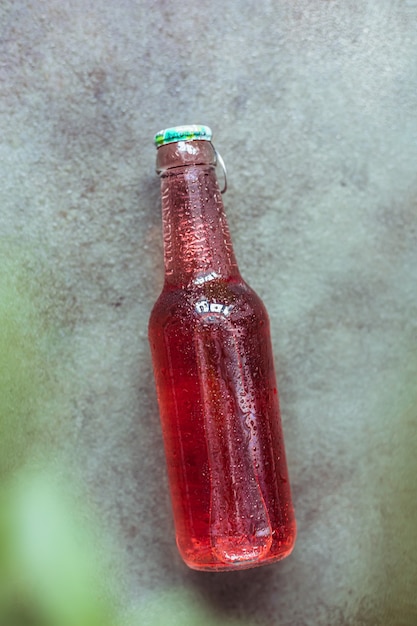 Photo vue de dessus de la bouteille avec des baies roses naturelles ou de la limonade à la pastèque avec des gouttes d'eau concept de détente d'été