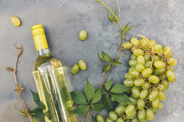 Vue de dessus de la bouteille de vin blanc vigne verte et raisin mûr sur fond de table en pierre grise vintage vin ...