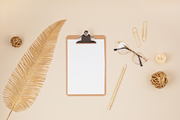 Vue de dessus sur le bureau avec bloc-notes, lunettes et accessoires dorés. Bureau à domicile, femme d'affaires, concept d'espace de travail élégant.