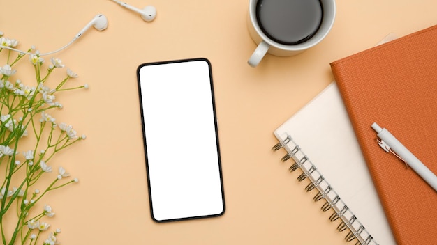 Vue de dessus de bureau de bureau féminin à plat avec maquette d'écran blanc de smartphone sur fond beige