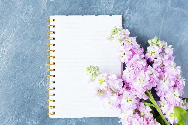 Photo vue de dessus de bureau, cahier vierge avec vue de dessus de fleurs violettes, mise à plat. copiez l'espace.