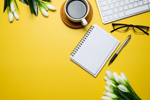 Vue de dessus de bureau jaune avec des consommables de clavier de fleurs sur l'espace de copie de bureau.