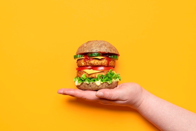 Vue de dessus de burger végétarien isolé sur fond orange Main tenant un burger de soja