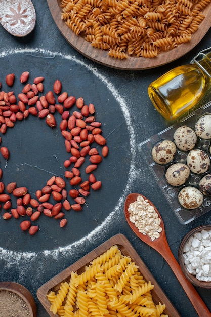 Vue de dessus des cacahuètes rouges fraîches avec des assaisonnements pour pâtes crues et des œufs sur le fond sombre couleur nourriture repas collation oeuf lait pâte écrou