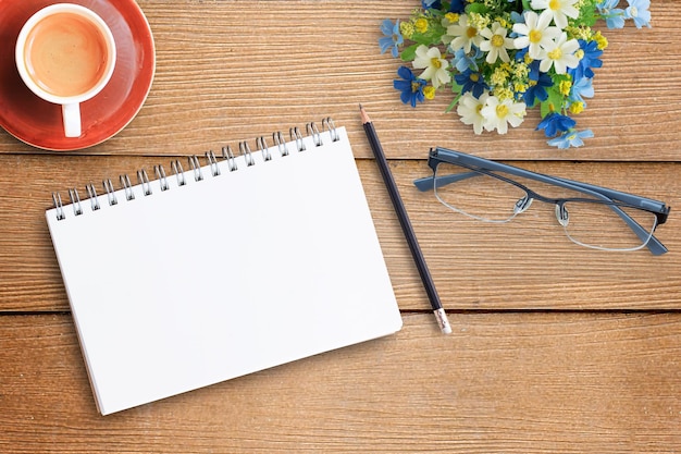 Vue de dessus avec cahier, lunettes, crayon et tasse de café