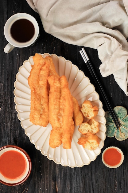 Photo vue de dessus cakwe (cakue) ou bâton de pain à l'huile chinoise est un aliment traditionnel indonésien pour le petit-déjeuner servi dans une assiette en céramique sur une table en bois. en indonésie, généralement servi pour la garniture au poulet congee.