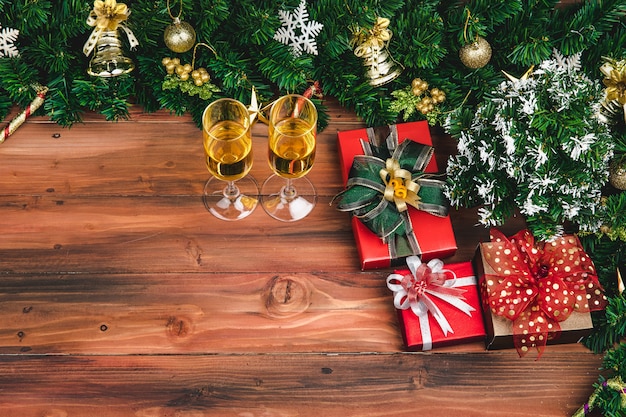 Vue de dessus de la célébration du nouvel an de Noël, chamange deux verres, coffrets cadeaux petit pin décoré avec des ornements du christ à la frontière. Poser sur l'espace de copie de fond de planche de bois.