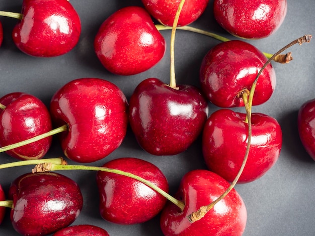 Vue de dessus de cerises douces juteuses et lumineuses sur fond sombre. Alimentation saine, mise à plat