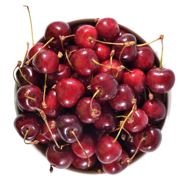 Vue de dessus des cerises rouges dans un bol blanc sur fond blanc