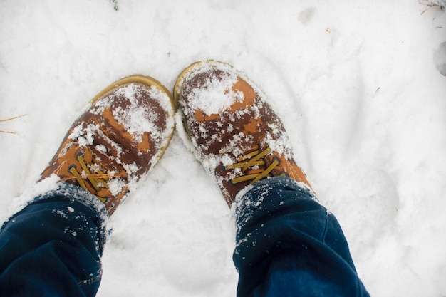 Photo vue de dessus des chaussures dans la neige fraîche. l'hiver. première vue des bottes marron