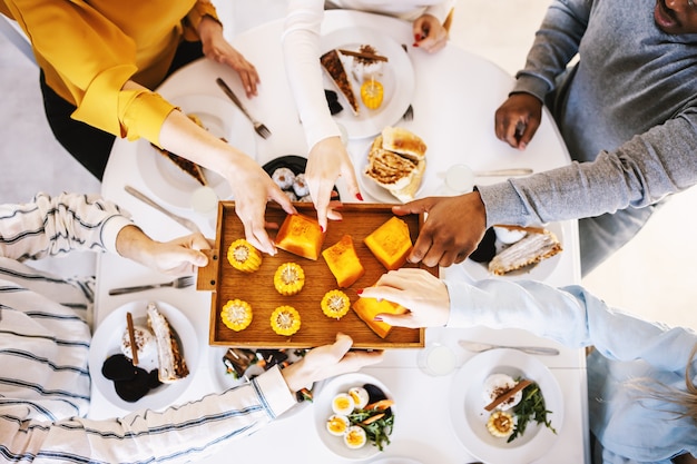 Photo vue de dessus de cinq amis multiculturels assis à table à manger et déjeuner sain.