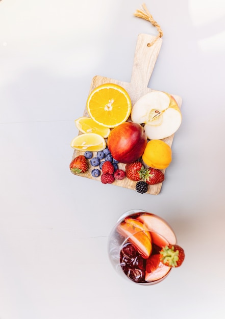 Vue de dessus des cocktails de fruits sur une table en bois blanc avec des baies et des feuilles de menthe