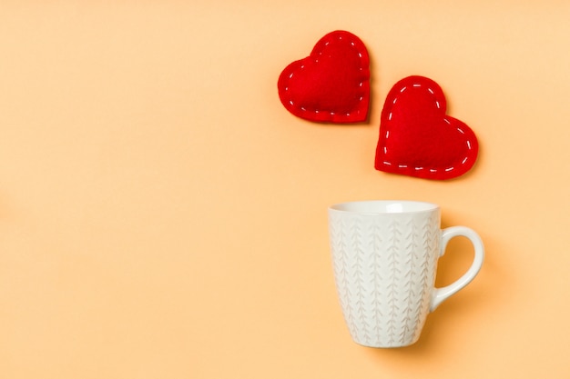 Vue de dessus des coeurs textiles rouges éclaboussant dans une tasse