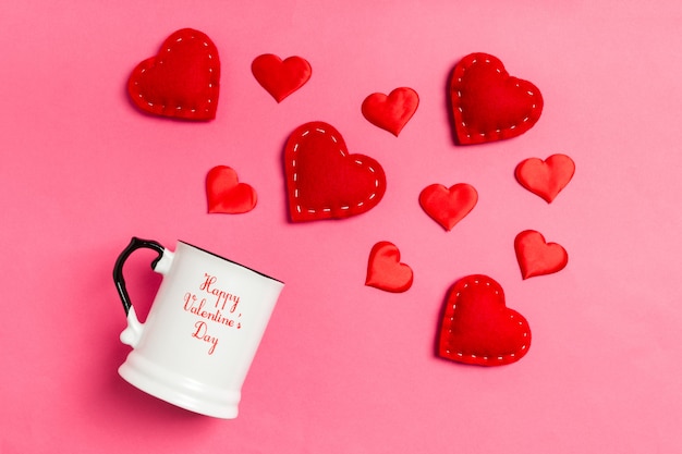 Vue de dessus des coeurs textiles rouges éclaboussant dans une tasse