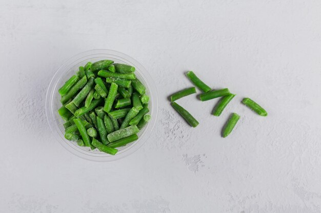 Vue de dessus de la composition avec des légumes surgelés biologiques sur une table en béton blanc