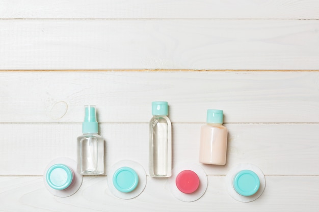 Vue de dessus composition de petites bouteilles et pots de voyage pour produits cosmétiques sur bois. Soins de la peau du visage avec copyspace