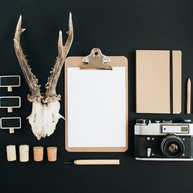 Vue de dessus, concept de photographe hipster plat laïc. Appareil photo rétro, cornes de chèvre, presse-papiers, journal d'artisanat sur tableau noir.