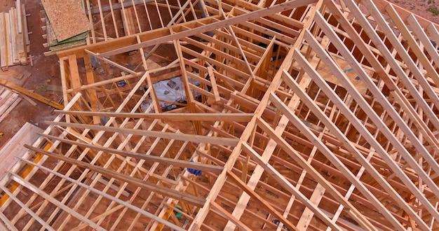 Vue de dessus de la construction travaillant sur les poutres du toit d'une maison en bois en construction