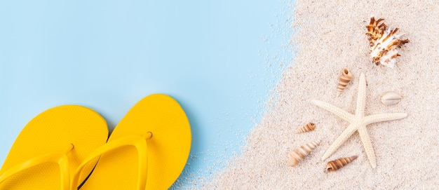 Photo vue de dessus avec copie espace de sandales jaunes avec étoile de mer et coquillages sable sur fond bleu