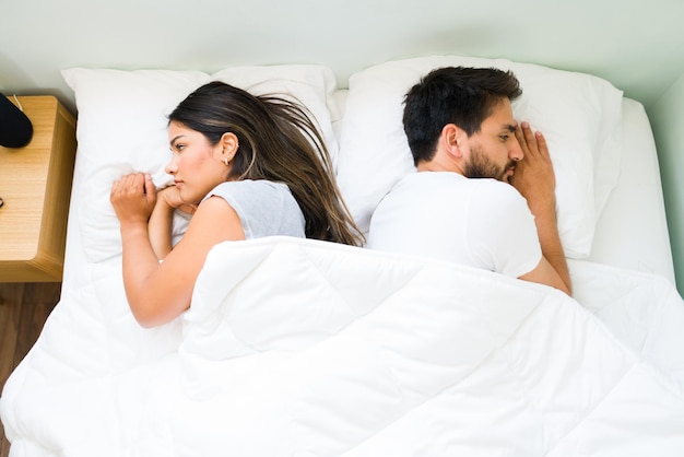 Vue de dessus d'un couple attrayant se tournant le dos et se sentant en colère l'un contre l'autre après s'être disputé avant de dormir