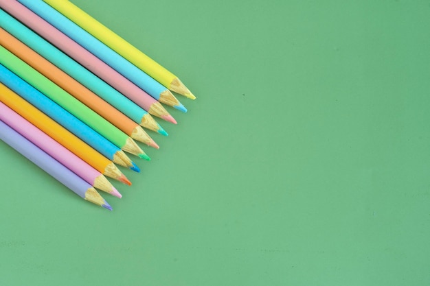 Vue de dessus de crayons de couleur pastel sur fond vert illustration concept éducation et retour à l'école