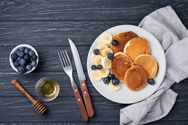 Photo vue de dessus des crêpes du petit déjeuner avec des tranches de banane et des couverts