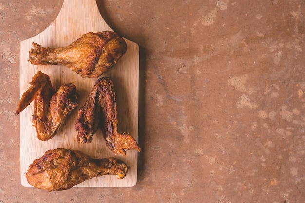 Vue de dessus des cuisses de poulet frites et des ailes sur un plateau en bois. Espace libre pour le texte