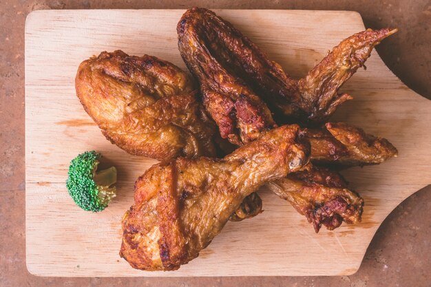 Vue de dessus des cuisses de poulet frites et des ailes sur un plateau en bois.