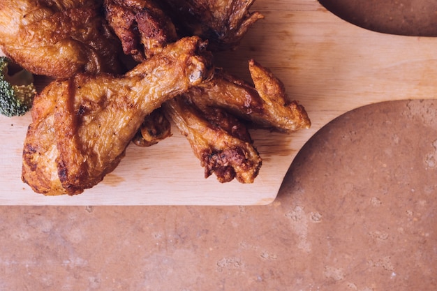 Vue de dessus des cuisses de poulet frites et des ailes sur un plateau en bois.