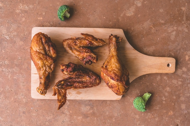 Vue de dessus des cuisses de poulet frites et des ailes sur un plateau en bois.