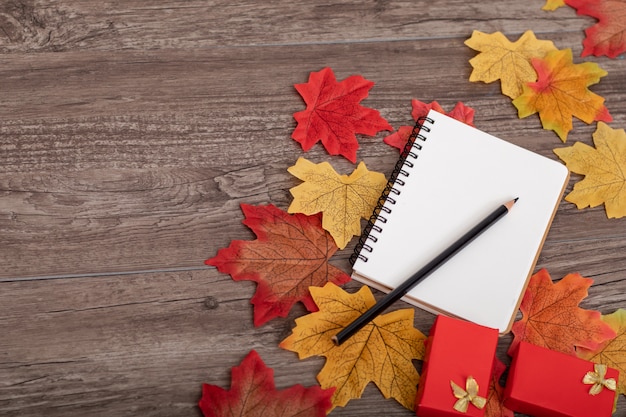 Vue de dessus décoration d&#39;automne coloré avec un crayon, boîte cadeau, note de papier, feuilles d&#39;érable